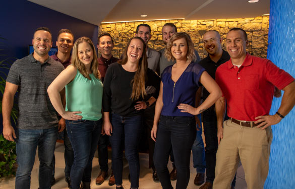 A group of ten ConnectWise employees are smiling at the camera. There are three women in the front and seven men around them. They are wearing business casual clothing.
